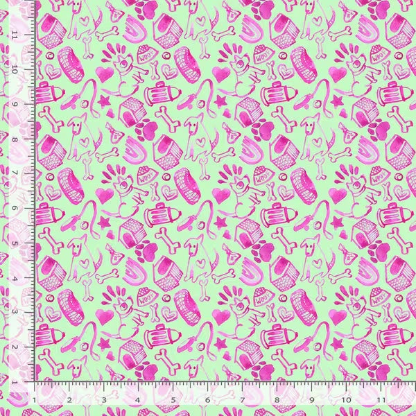 Fabric with pink dog-themed patterns on a green background, measured against a ruler.