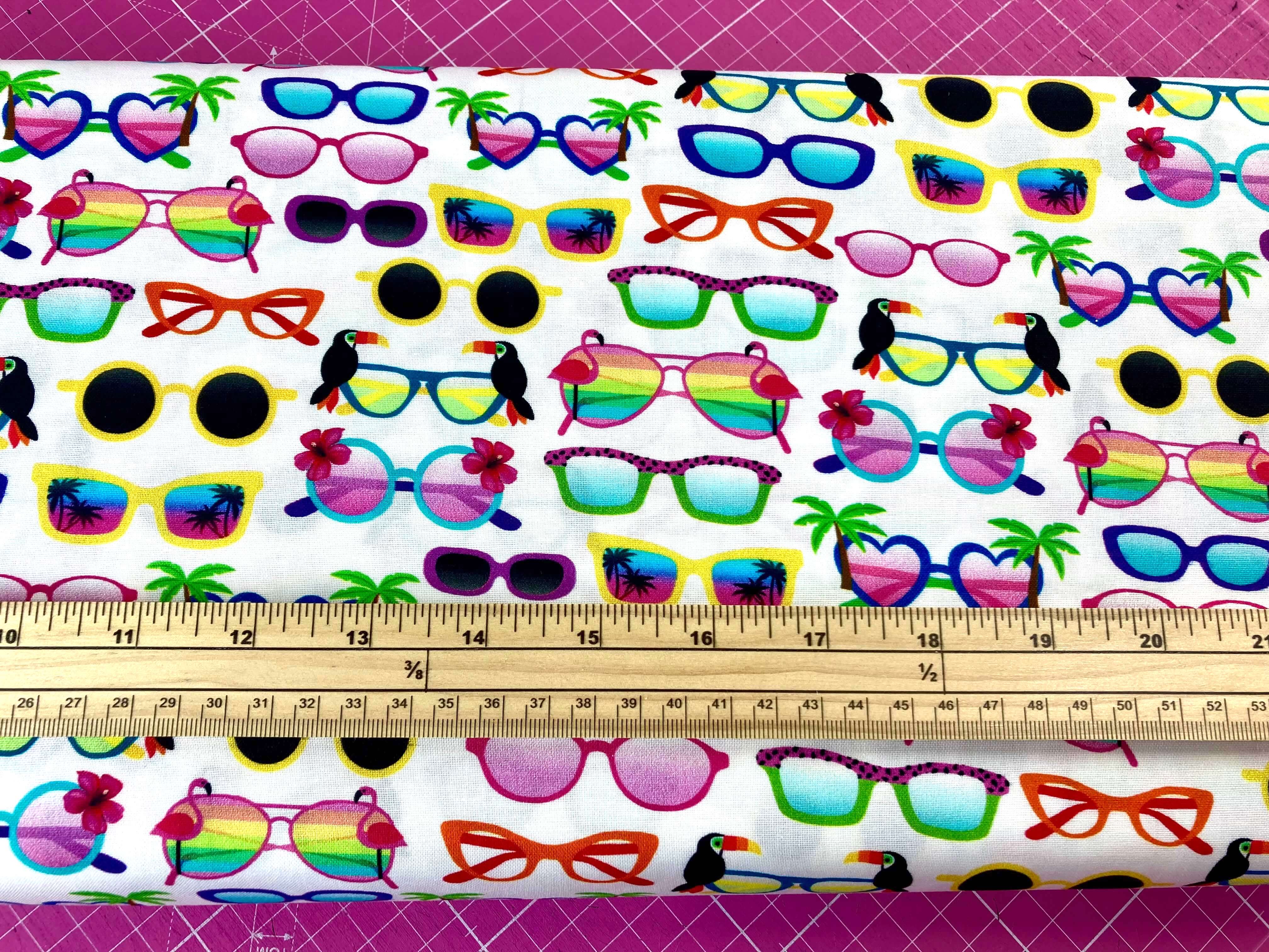 tropical coloured sunglasses cotton fabric on a white background with a ruler