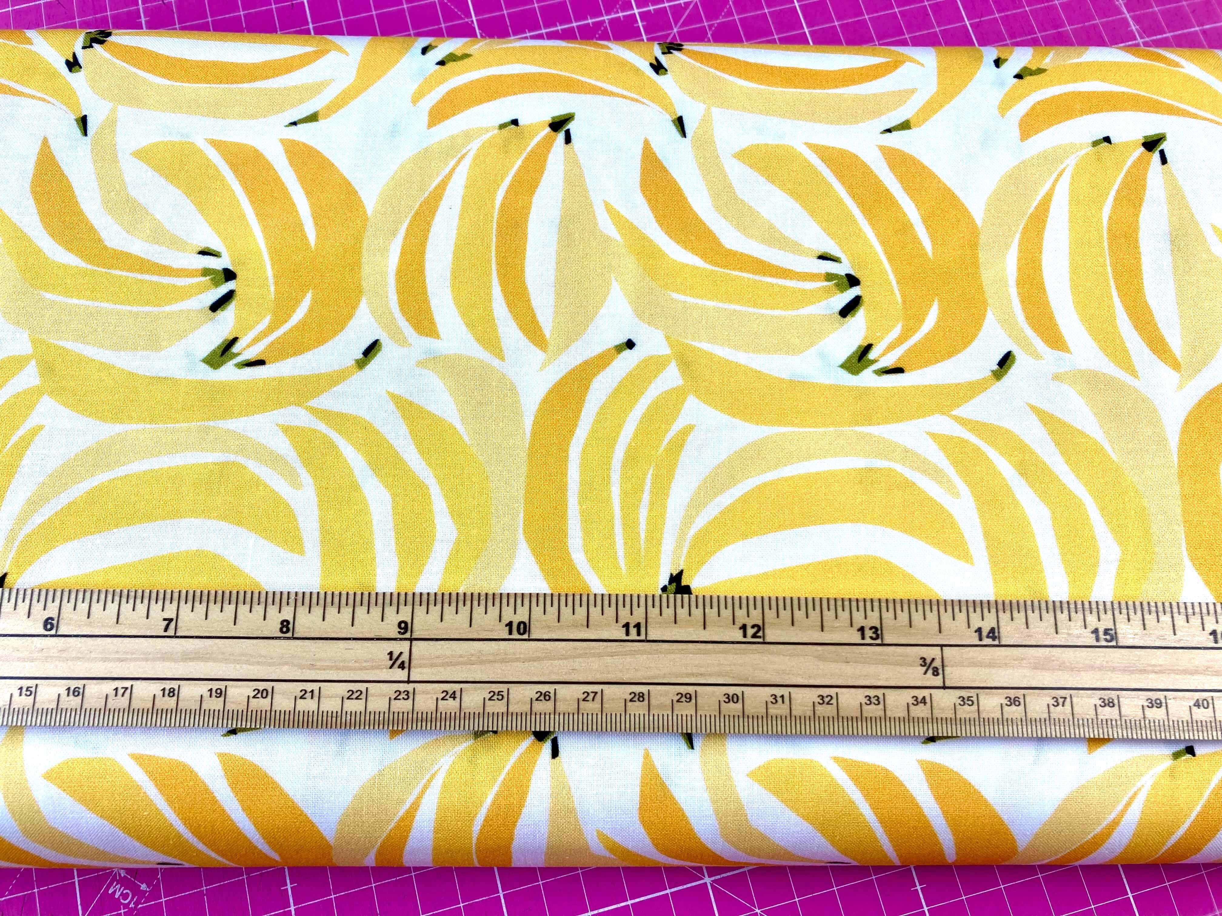 bunches of yellow bananas on white cotton fabric with a ruler